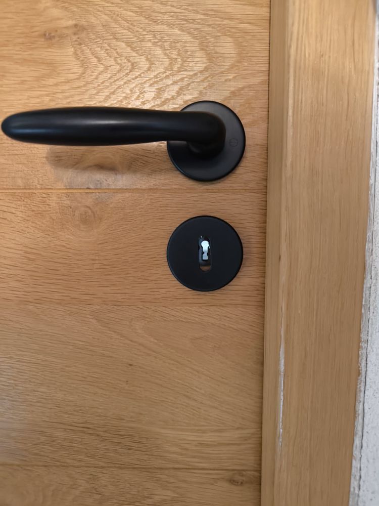 Poignée noire et serrure remplacée sur une porte en bois clair après un blocage